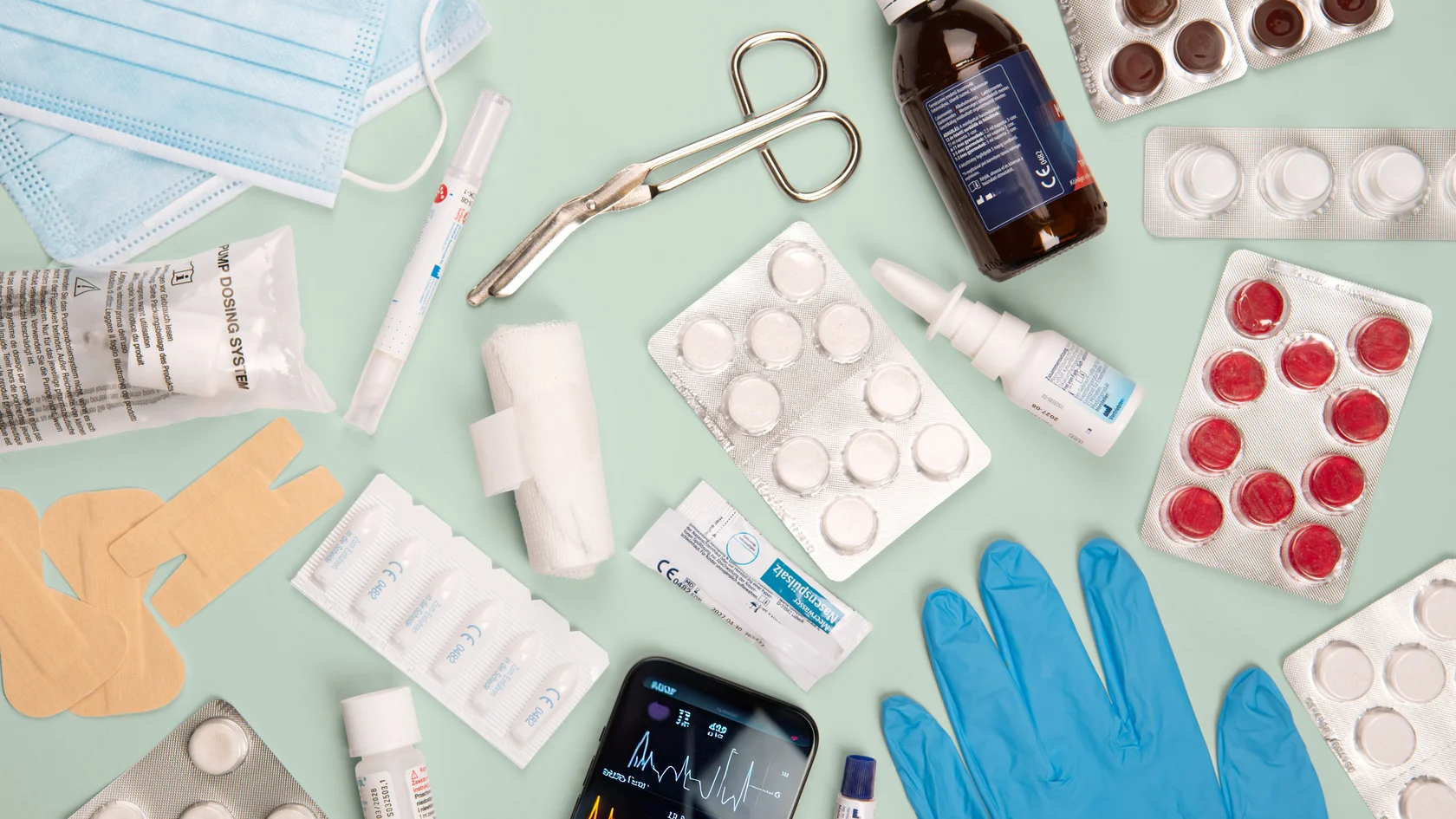 Medizinische Utensilien Medizinische Utensilien wie Masken, Tabletten, Handschuhe und Geräte flach auf blauem Hintergrund arrangiert.