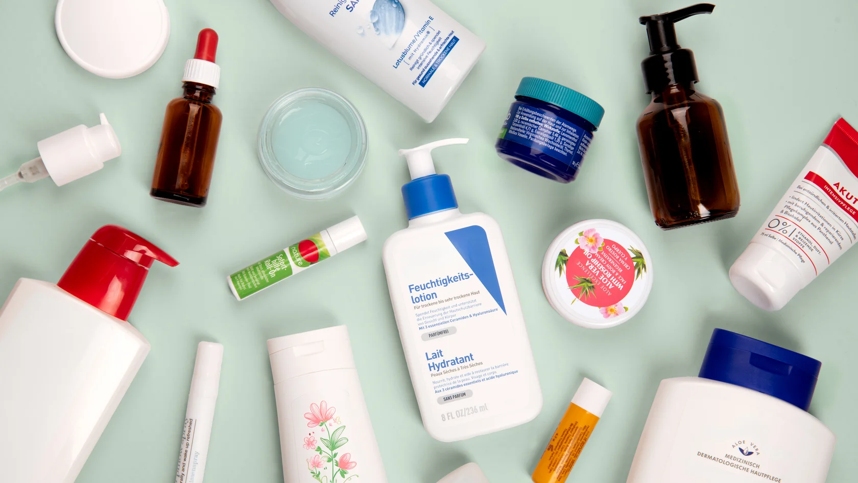 Pflegeprodukte im Überblick Verschiedene Hautpflegeprodukte wie Lotionen, Cremes und Lippenpflegestifte auf blauem Hintergrund arrangiert.