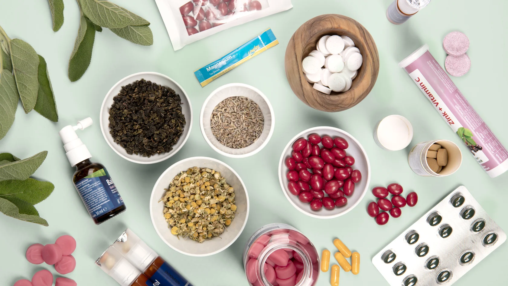 Natürliche und pharmazeutische Vitalstoffe Verschiedene Kräuter, Tabletten, Kapseln und Nahrungsergänzungsmittel auf hellgrünem Hintergrund arrangiert.