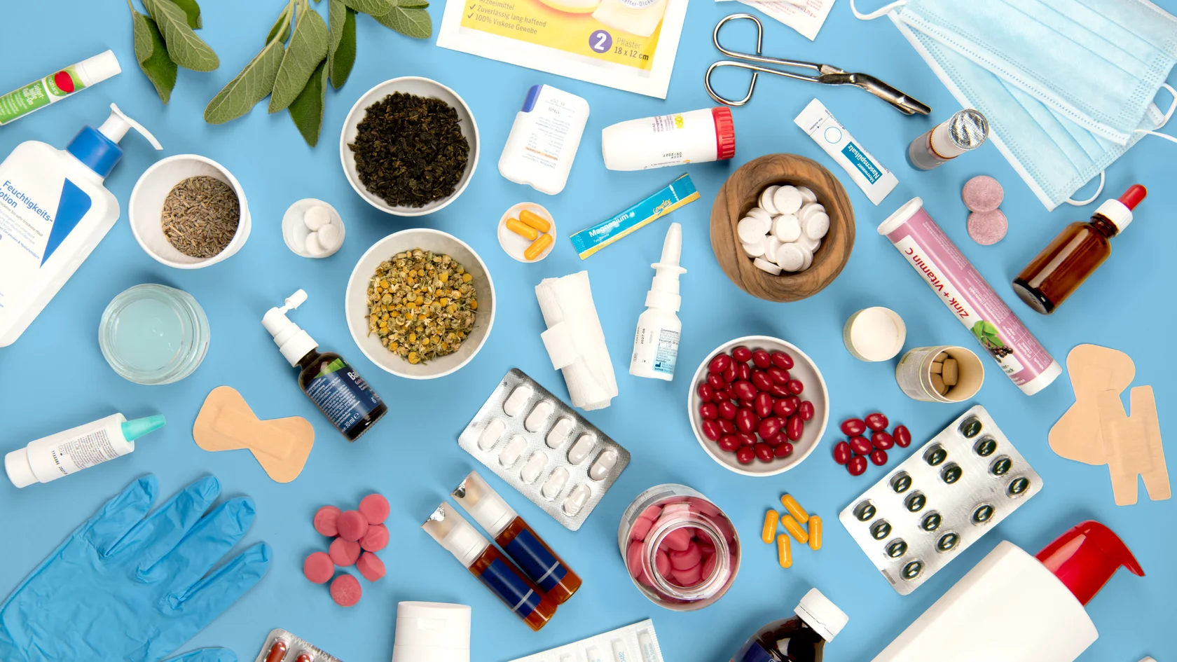 Hausapotheke zwischen Natur und Medizin Verschiedene Medikamente, Kräuter und medizinische Utensilien flach auf hellblauem Hintergrund arrangiert.