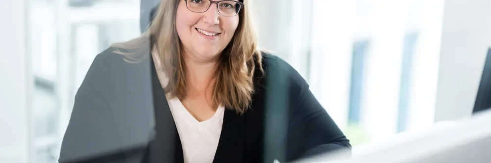 Arbeiten am Computer bei Tageslicht Eine Person mit langen Haaren sitzt an einem Schreibtisch und arbeitet an einem Computer.